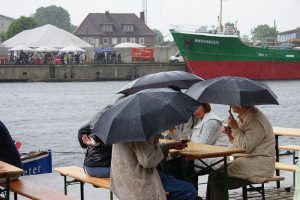 Beinhart im Nehmen: Beim Hafenfest in Harburg gibt es kein schlechtes Wetter, nur unpassende Kleidung - oder einen Schirm. Im Hintergrund: Die "Greundiek" aus Stade. Foto: Heingerd Detjen