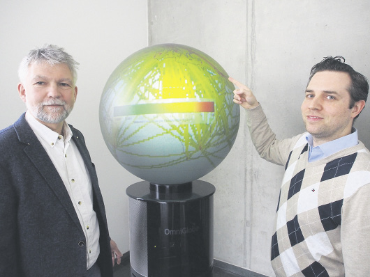 Professor Dr. Volker Gollnick (links) und Dr. Florian Linke vor dem Globus, der die Globalwirkungen des Flugverkehrs darstellt und im „Goldfisch“-Foyer, Blohmstraße 20, im Harburger Binnenhafen steht. Hier ist das Institut zu Hause.