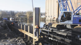 Von einem Ponton aus werden die Spundbohlen mit schwerem Gerät sechseinhalb Meter tief in den Boden gerüttelt und gerammt. Rechts: Hier wird der historische Kran demontiert. Foto: Wolfgang Becker